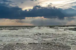 Aufgewühlte stürmische Ostsee mit hohen Wellen, weißer Gischt und dramatischen dunklen Gewitterwolken.